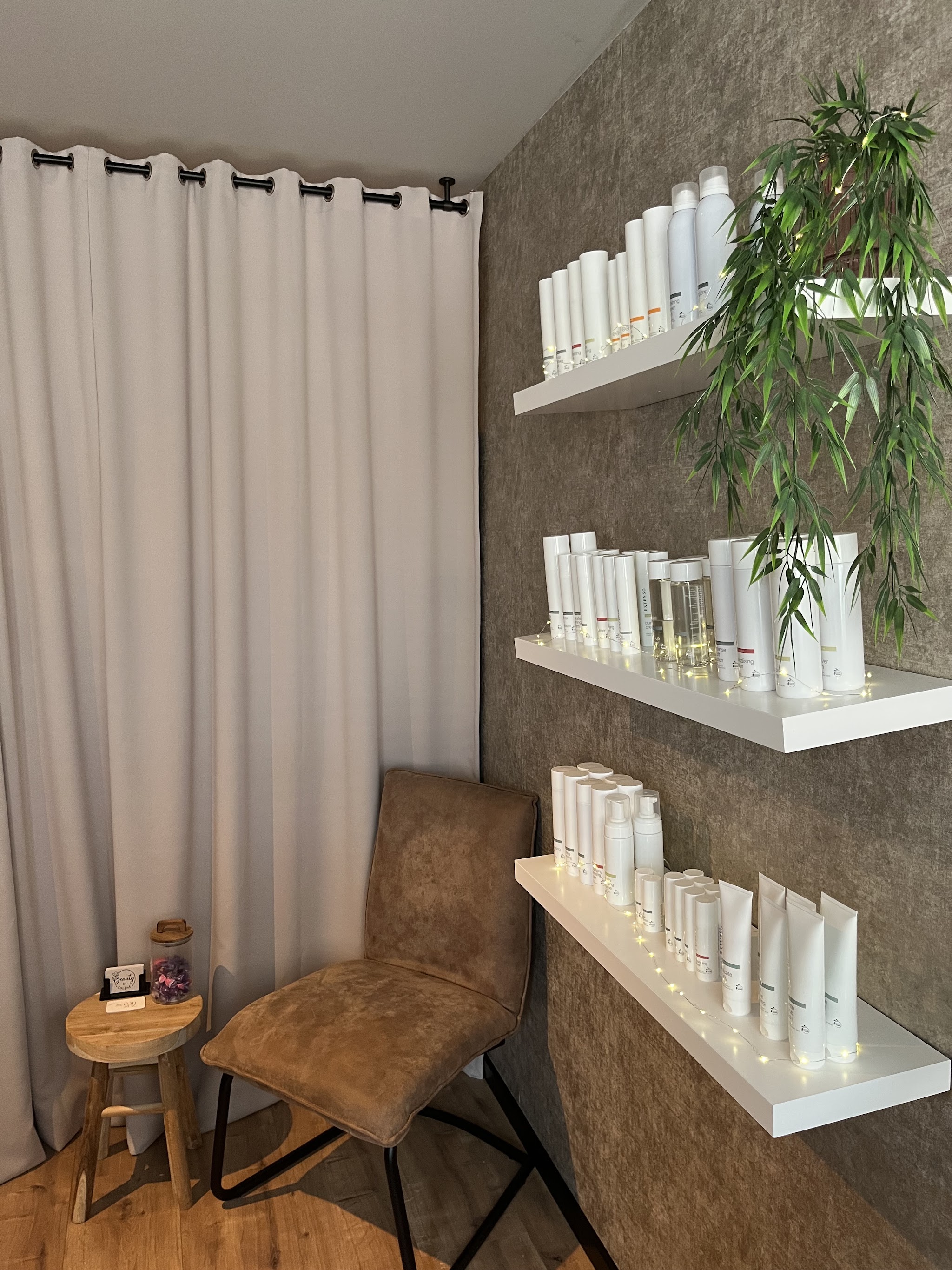 Witte zwevende plankjes vol Extenso-producten, een plant en een fauteuil in de behandelkamer
