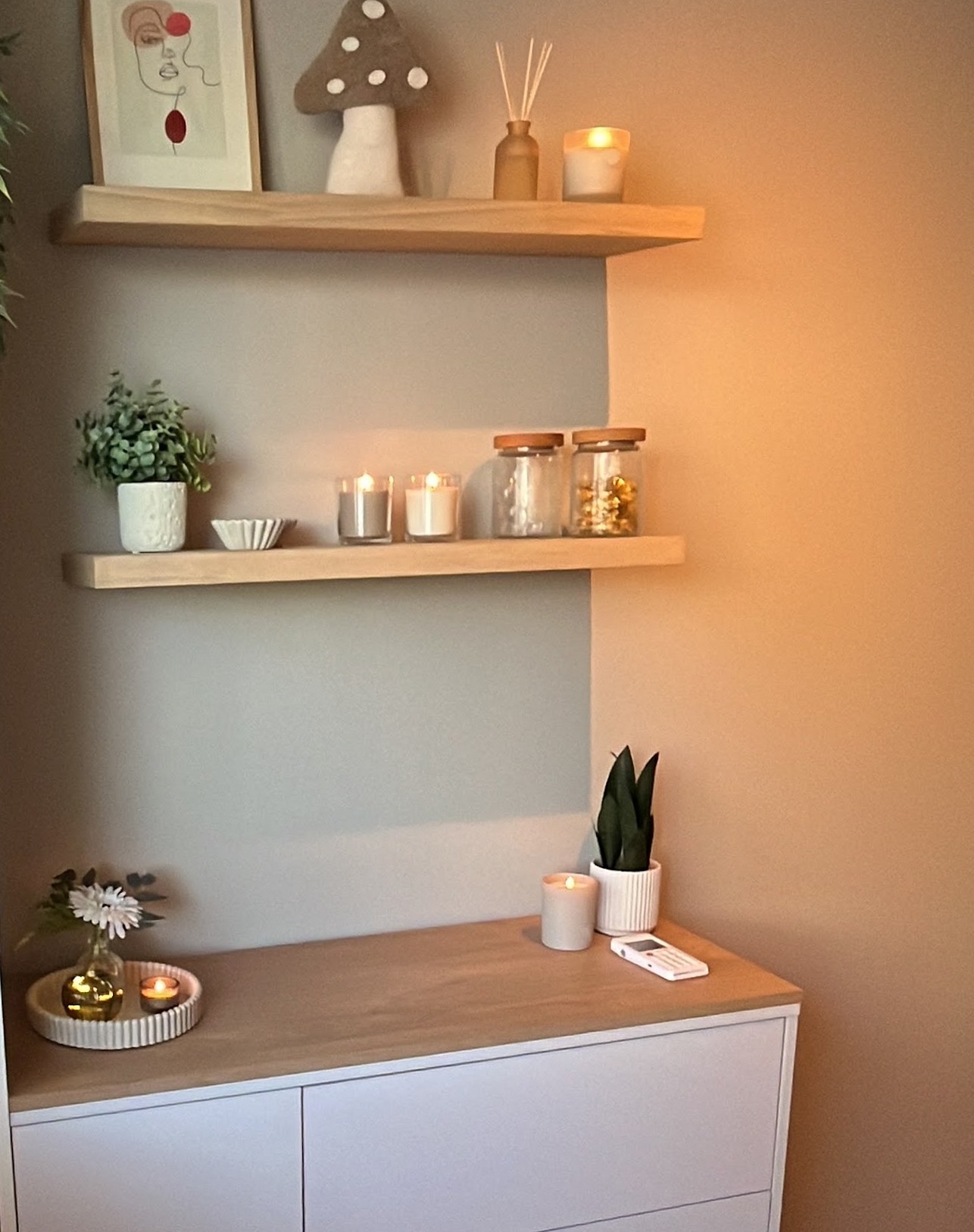 Een hoek van de behandelkamer met kaarsjes op houten plankjes, een witte kast en een trolley met producten